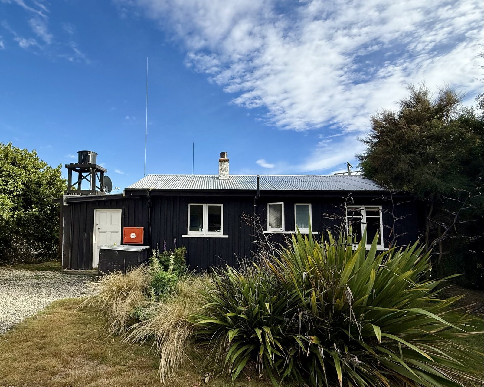 The Black Shack exterior with native flax, Lake Hawea